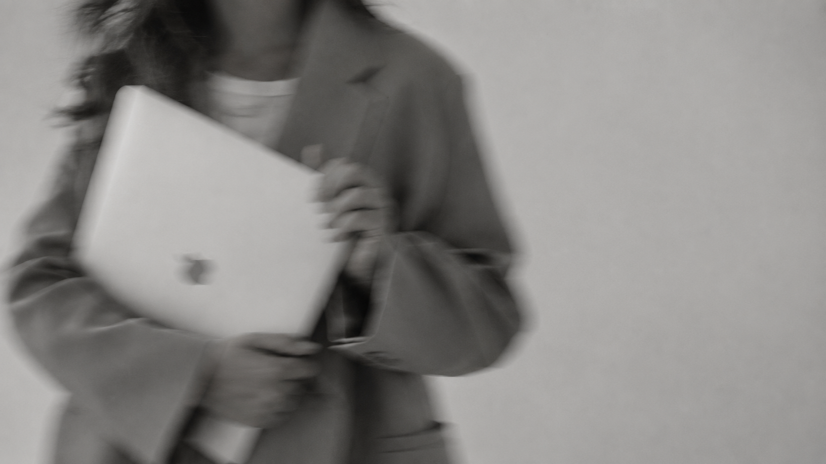 Business owner in a blazer carrying a laptop